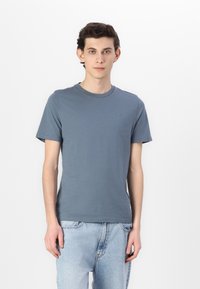 Korte ermer blå bomulls t-skjorte med rund hals og lite logo på brystet, kombinert med lyseblå denimjeans.