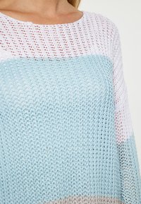Pullover leggero in maglia con un gradiente di colori blu pastello, bianco e beige. Tessuto testurizzato con un design a trama larga e aperta.