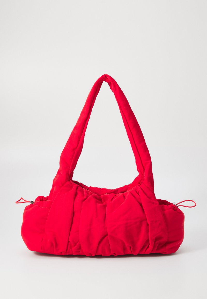 Sac à main en tissu rouge avec un design rembourré, doté d'une large sangle courbée et de détails froncés. Comprend un cordon de serrage sur un côté.