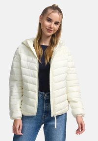 Pufferjack in off-white, met een capuchon, gequilt ontwerp, ritssluiting en geribbelde accenten. Gecombineerd met donkere spijkerbroeken.