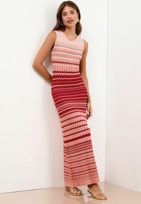 Abito senza maniche in maglia con motivo a zigzag in tonalità di rosa e rosso, dalla silhouette aderente e un orlo lungo e fluido.