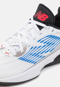 Athletic shoe with a white textile upper, featuring blue stripes, silver accents, and black heel collar. White laces and textured sole.