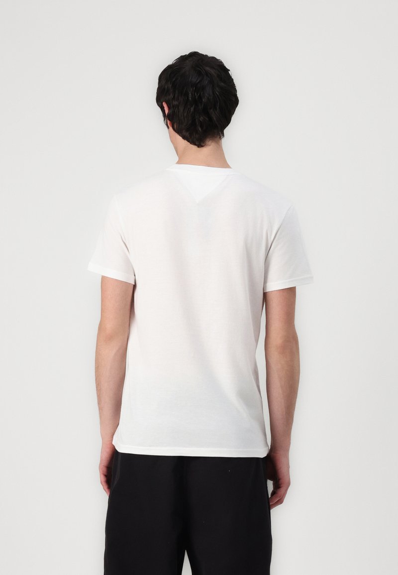 Camiseta de algodón blanca con mangas cortas, escote redondo y textura suave; presenta un sutil detalle en forma de V en la parte posterior.