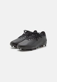 Schwarze Fußballschuhe mit strukturiertem Synthetik-Obermaterial, flachen Schnürsenkeln und geformten Gummispikes für Halt auf Gras. Minimalistisches Design.