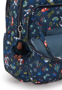 Marine rygsæk med farverige rum- og robottryk, med en lynlås åben frontlomme og en fluffy mørkeblå gorilla nøglering hængende fra lynlåsen.
