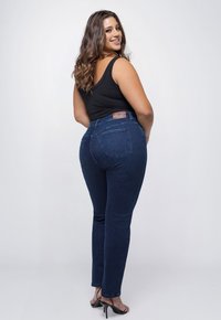 Donkerblauwe denim jeans met een getailleerd ontwerp, middelhoge taille en twee achterzakken. Het materiaal heeft een zachte textuur en lichte stretch.