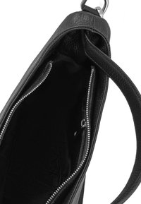 Sac à main en cuir noir avec un extérieur texturé, comportant deux compartiments zippés et une doublure en tissu lisse. Sangle réglable incluse.