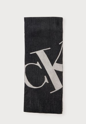 Black and white ribbed knit scarf folded, featuring large contrasting stylized letters partially visible on the fabric.