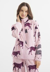 Różowa polarowa kurtka z wysokim kołnierzem, z wzorem w zebra w czerni i purpurze. Materiał jest miękki i puszysty, z zapięciem na zamek.