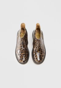 Bottes chelsea à imprimé léopard en matériau brillant avec des panneaux latéraux élastiqués et une semelle cousue, présentant un logo doré sur la semelle intérieure.