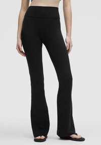 Svarta utsvängda leggings gjorda av en slät, elastisk tyg. Har ett högt midjeband och en åtsittande siluett ner till de utsvängda anklarna.