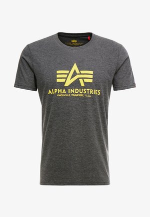 Šedé tričko krátky rukáv z bavlnenej zmesi. Obsahuje žlté logo "Alpha Industries" so štylizovaným písmenom A a tromi pruhmi. Neformálny dizajn.