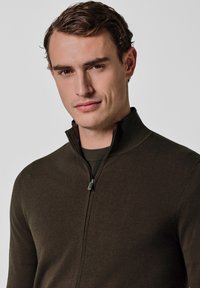 Ciemnobrązowy sweter na zamek wykonany z elastycznej tkaniny, z wysokim kołnierzem i gładką fakturą, odpowiedni do codziennego noszenia.