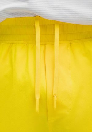 Shorts jaunes à taille élastique avec cordons assortis. Texture lisse, détails cousus et taille froncée pour un ajustement réglable.