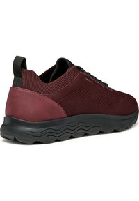 Scarpe sportive color bordeaux con tomaia in maglia testurizzata, tacco in gomma liscia e suola a motivo ondulato. Lacci neri e dettaglio sul loop del tallone.