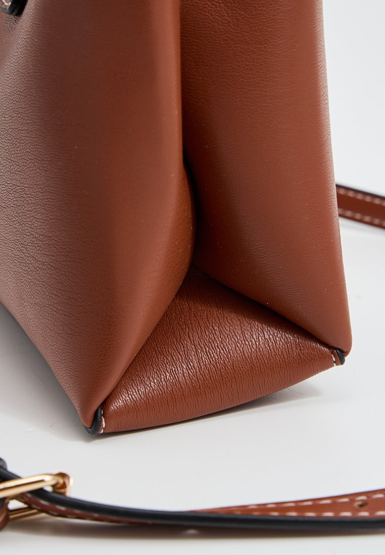 Sac à main en cuir synthétique marron avec une surface texturée, un fond triangulaire et une bandoulière amovible avec des détails de couture contrastants.