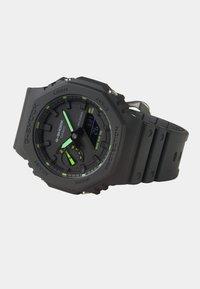Montre Casio G-Shock avec un boîtier et un bracelet en résine noire, un grand affichage analogique-numérique et des accents verts. Résistante à l'eau jusqu'à 20 bars.
