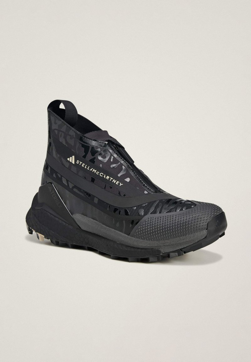 Zwarte hoge sportieve schoen met een strakke, gestructureerde oppervlakte, voorzien van een ritssluiting, met patroonaccenten en een robuuste zool voor grip.