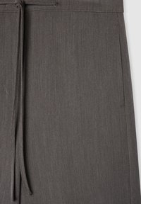 Szare spodnie wykonane z miękkiego, fakturowanego materiału, z elastycznym paskiem i bocznymi kieszeniami, o schludnym i dopasowanym wyglądzie.