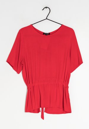 Blusa roja de manga corta con escote redondo, cintura elástica y detalle anudado en el dobladillo. Textura suave y diseño de ajuste relajado.