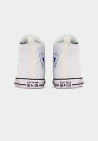 Ζευγάρι λευκά ψηλά παπούτσια Converse All Star, εμφανιζόμενα από πίσω σε λευκό φόντο.