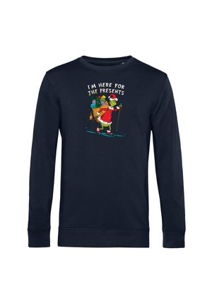 Mørkeblå sweatshirt med lange ærmer, med en tegneseriefigur i en julesweater, der står på ski med gaver; teksten lyder "JEG ER HER FOR GAVERNE."