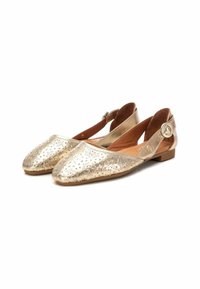 Ballerine dorate metallizzate con punta affilata, caratterizzate da intricati motivi intagliati, una cinturina regolabile e un tacco basso. Fodera in pelle marrone.