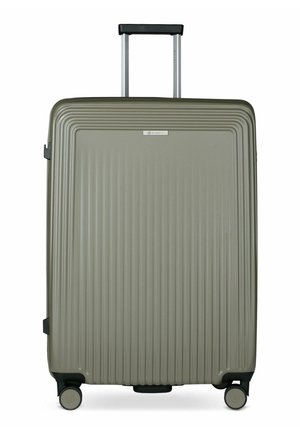 Grande valise rigide grise avec des rainures verticales, quatre roues et une poignée télescopique noire étendue.