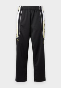 Black athletic pants with an elastic waistband. Features side stripes in white and yellow, and smooth, lightweight fabric texture.