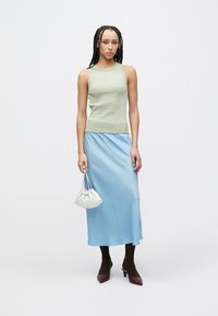 Light green sleeveless top, blue satin skirt, white gathered handbag, brown tights, and burgundy heels. Simple design with smooth textures.