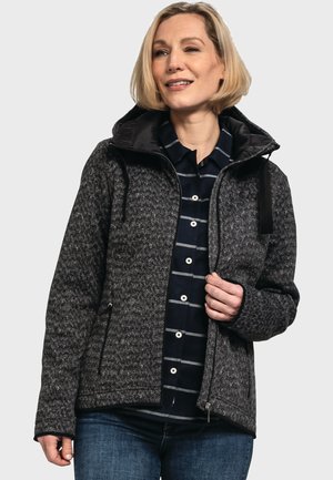 Grau gemusterte Jacke mit einem Reißverschluss an der Vorderseite, großer Kapuze und zwei seitlichen Taschen, kombiniert mit einem marineblau gestreiften Shirt darunter.