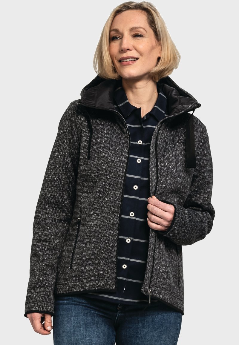 Grau gemusterte Jacke mit einem Reißverschluss an der Vorderseite, großer Kapuze und zwei seitlichen Taschen, kombiniert mit einem marineblau gestreiften Shirt darunter.