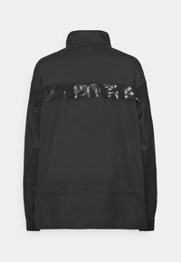 Schwarze Jacke mit hohem Kragen, glänzender schwarzer Akzentstreifen entlang des Rückens, elastischen Bündchen und einer leichten, glatten Textur.