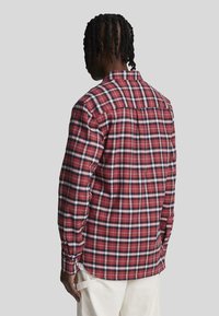 Camicia a scacchi rossa in tessuto, con un motivo a quadri, caratterizzata da accenti bianchi e blu navy, maniche lunghe e colletto con bottoni.