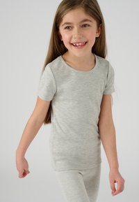 Camiseta gris de manga corta hecha de un tejido suave, con cuello redondo y un corte holgado, combinada con leggings grises a juego.