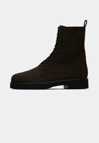 Bottes à lacets en cuir marron, montant à la cheville, avec un bout rond, une semelle renforcée et une texture lisse. Comprend une languette et des lacets robustes.