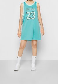 Turkos nätbasketklänning med "JORDAN" och "23" tryckt på framsidan; matchad med vita strumpor och skor. En enkel, sportig design.