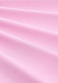 Ljusrosa bomullstyg med en slät yta, som visar mjuka veck och fåror, lämplig för kläder eller möbelklädsel.