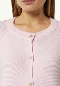 Light pink cardigan with a textured knit pattern, featuring a round neckline and five buttons down the front, showcasing a smooth fabric finish.