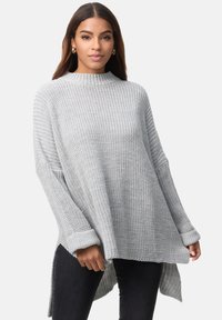 Hellgrauer Strickpullover mit hohem Kragen, überschnittenen Schultern, gerippten Ärmeln und einem längeren hinteren Saum. Weiche Textur und lockerer Schnitt.