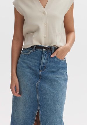 Beige sleeveless top with a V-neck and buttons, paired with a blue denim skirt featuring a front slit and a black belt.
