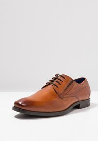 Chaussure habillée en cuir marron avec une finition polie, bout rond, design à lacets et panneau latéral texturé ; semelle en caoutchouc robuste.