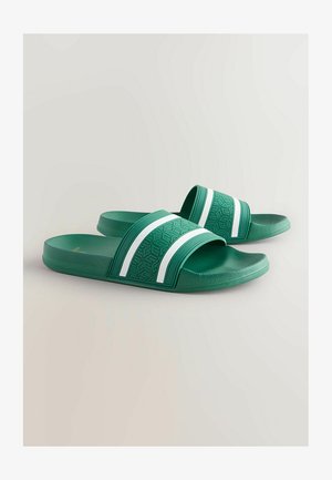 Rohelised liugunud sandaalid, mis on valmistatud tekstureeritud kummist, kahe valge triibuga laial rihmal ja mustrilise jalgealusega.