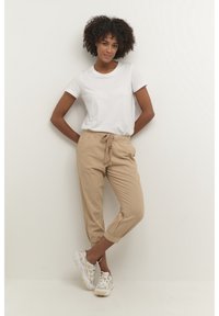 Lichtgewicht wit katoen t-shirt met korte mouwen, gecombineerd met beige broek met trekkoord, voorzien van enkelmanchetten en een ontspannen pasvorm.
