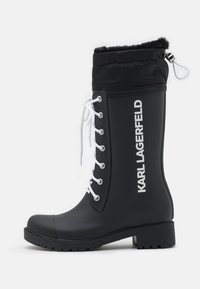 Black rubber rain boot with white laces and bold "KARL LAGERFELD" branding. Features a soft, black fabric lining and a textured sole.