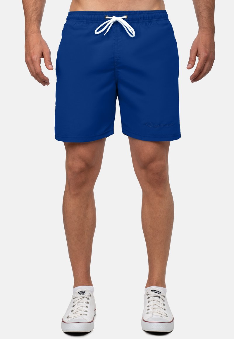 Blauwe zwemshorts met een elastische tailleband, witte trekkoorden en subtiele logo-details. Gladde stof en een ontwerp dat hoger dan de knie valt.