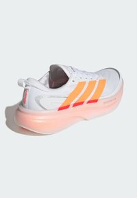 Scarpa da ginnastica bianca con accenti arancioni e rossi, tomaia in mesh strutturato e suola traslucida con tonalità rosa. Presenta tre strisce laterali.