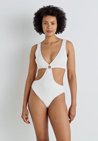 Maillot de bain blanc une pièce avec un décolleté en V profond, des côtés découpés et un détail de cercle au centre. Le tissu texturé rehausse l'intérêt visuel.