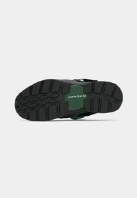 Zwarte sneaker met groene accenten, gestructureerde rubberen zool en zichtbaar merkimago. Bevat een gestroomlijnd ontwerp met een gevoerde enkelkraag.