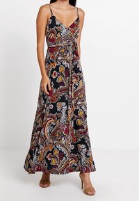 Robe maxi noire avec un motif cachemire mettant en valeur des accents rouges, jaunes et blancs. Des bretelles spaghetti et une taille nou ée définissent la silhouette.